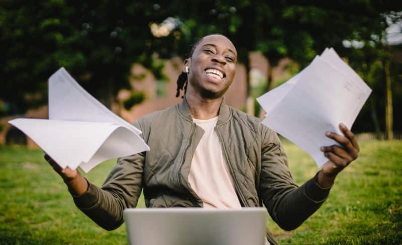 Estudiante feliz con apuntes frente al portátil